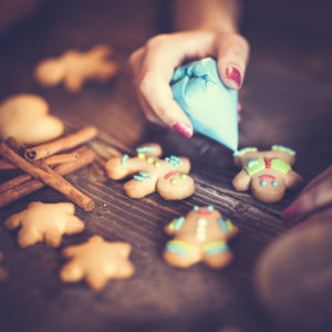 Young woman baking and decorating Gingerbread Man and other cookies.